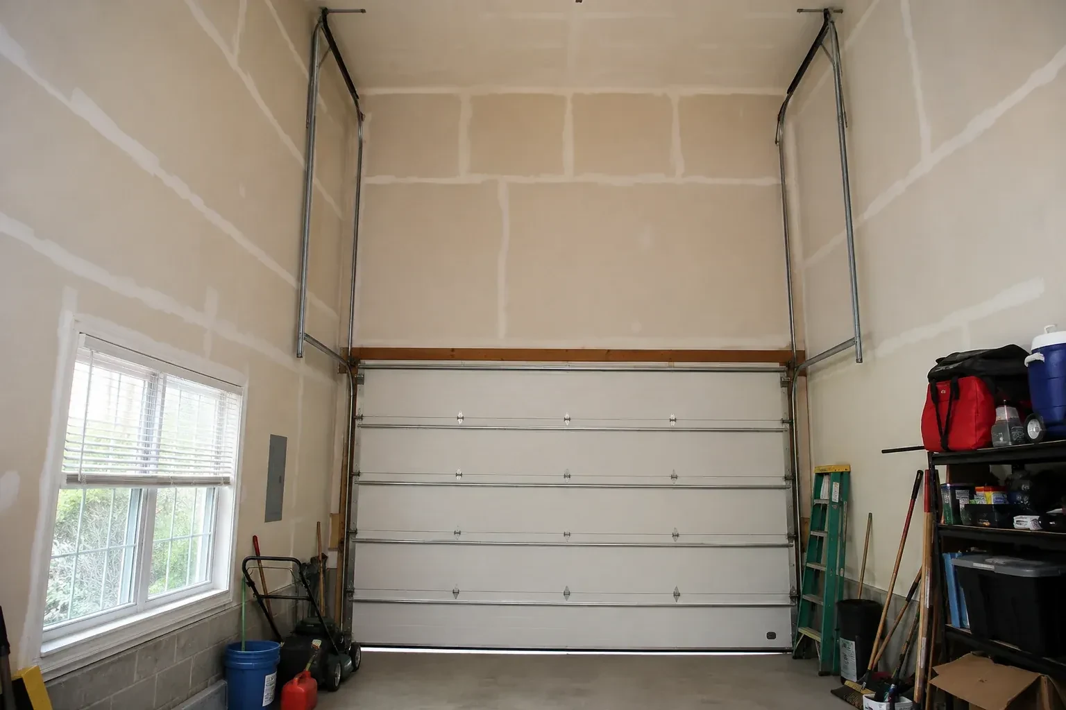 Tall garage interior with a sectional door and tracks extending into overhead space. — High-Lift Garage Door Conversion, Toronto